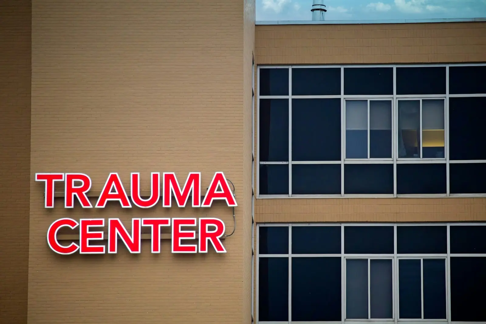 Bir hastane binasının duvarında kırmızı neonla yazılmış “TRAUMA CENTER” tabelası.